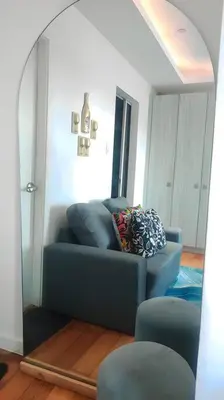 a living room with a blue couch and a mirror at Aveline Suites Luna,1br, Rockwell side in Manila