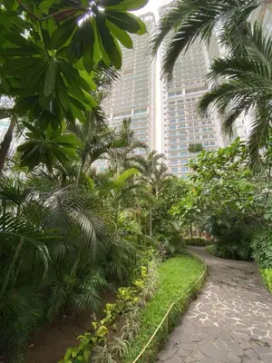 a garden with palm trees in front of a building at Aveline Suites Luna,1br, Rockwell side in Manila