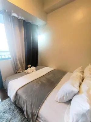 two beds in a room with a window at Sun and Moon D'wood air residences makati in Manila
