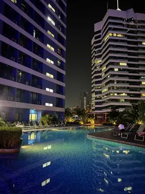 a large swimming pool at night with two tall buildings at Sun and Moon D'wood air residences makati in Manila