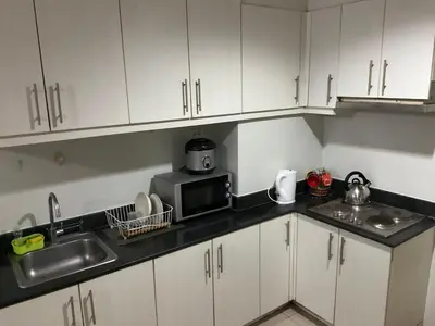 a kitchen with white cabinets and a sink and a microwave at SEA 2-BR Unit with Free Parking near Mall of Asia in Manila