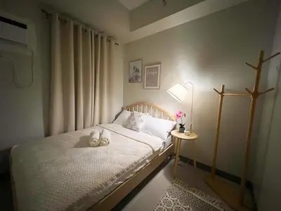 a small bedroom with a bed and a lamp at Casa Dona Suites at SMDC Charm Residences in Manila