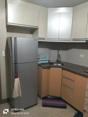 a kitchen with white cabinets and a stainless steel refrigerator at Two Palm Tree by Nadz in Manila