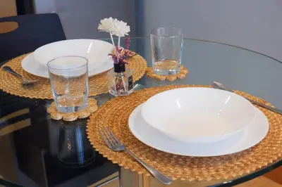 a glass table with two plates and glasses on it at Condo in Makati with Fast WiFi, Free Pool, Netflix and Own Balcony in Manila