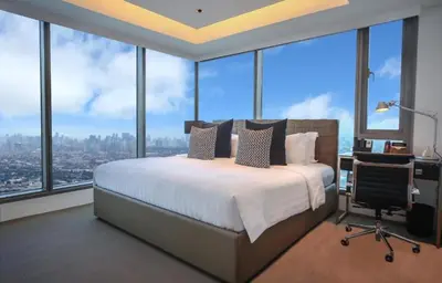 a bedroom with a bed and a desk and windows at Azure Urban Paris Hilton Beach Resort in Manila