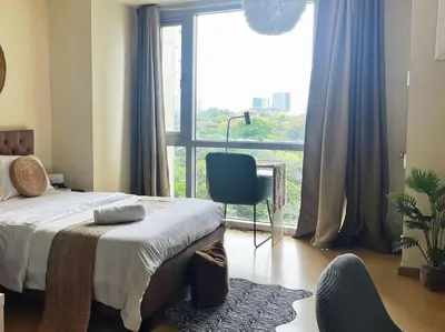 a bedroom with a bed and a chair and a large window at Jane in the City! In Avant, BGC in Manila