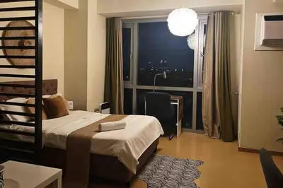 a bedroom with a bed and a window with a city at Jane in the City! In Avant, BGC in Manila