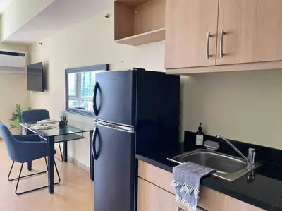 a kitchen with a refrigerator and a sink and a table at Jane in the City! In Avant, BGC in Manila