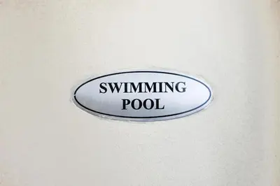 a sign that reads swimming pool hanging on a wall at Solana in Avant BGC parking with fee in Manila
