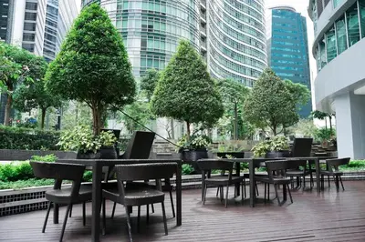 a group of tables and chairs with trees and buildings at Solana in Avant BGC parking with fee in Manila