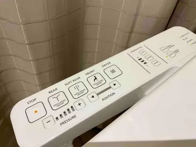 a white remote control sitting on top of a toilet at Tarzan in the City! in Avant BGC parking with fee in Manila