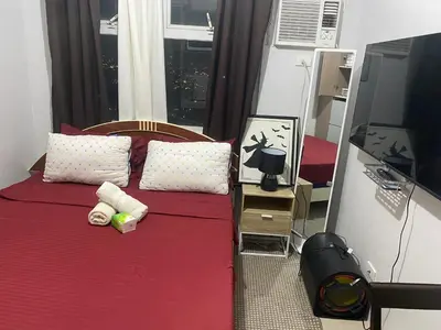 a bedroom with a bed with red sheets and a window at Pierrecondotel in Manila