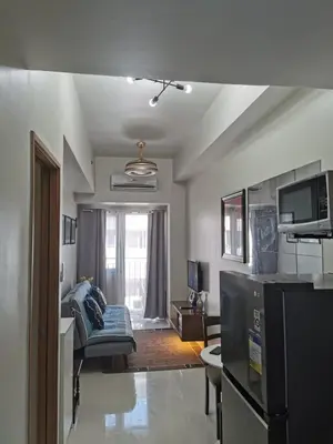 a kitchen and living room with a couch and a television at Mall of Asia shore 3 residence in Manila