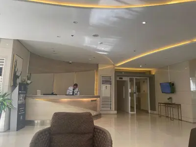 a person standing in a lobby with a counter at Grace Residences Condo 1 BR Poolview near McKinley BGC in Manila
