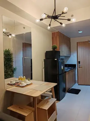 a kitchen with a wooden table and a black refrigerator at Haven of Tranquility Suite - SMDC Shore 3 (MOA) in Manila