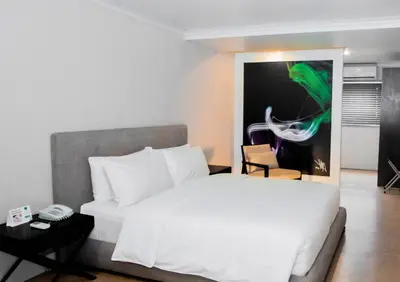a bedroom with a white bed and a painting on the wall at Green Sun Hotel in Manila