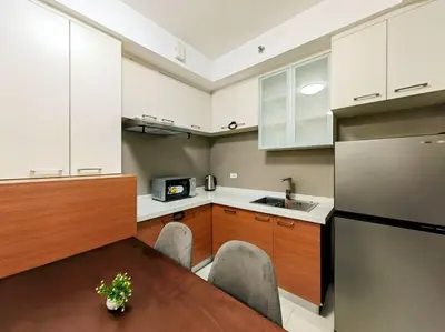 a kitchen with a wooden table and a refrigerator at 1BR Condotel Suite at Sunshine100 City Plaza #SS02 in Manila