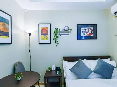 a bedroom with a bed and a table and pictures on the wall at 1BR Condotel Suite at Sunshine100 City Plaza #SS03 in Manila
