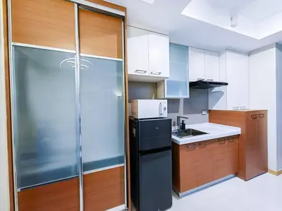 a kitchen with a black refrigerator and wooden cabinets at 1BR Condotel Suite at Sunshine100 City Plaza #SS03 in Manila