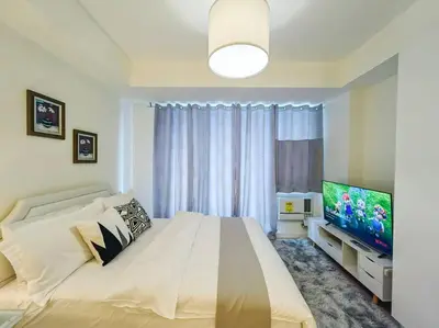 a bedroom with a large bed and a flat screen tv at 1BR Condotel at Azure Urban Resort Near Airport #AZ03 in Manila