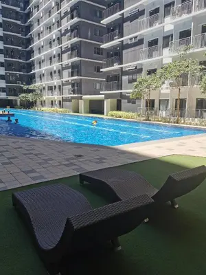 a swimming pool with a bench in front of a building at Shore 3 residence mall 'of Asia in Manila