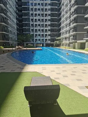 a swimming pool with a bench in front of some buildings at Shore 3 residence mall 'of Asia in Manila
