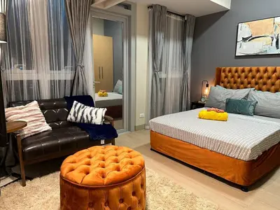 a bedroom with a bed and a leather couch at Elegant 1 BR Condo with Balcony in Uptown Parksuites II, BGC in Manila