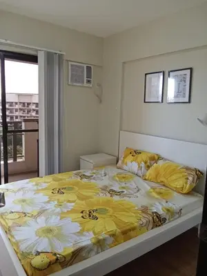 a bedroom with a bed with a yellow and white comforter at Asteria Lovely Staycation in Manila