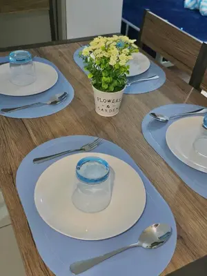 a table with plates and spoons and a vase of flowers at Serenity Acqua Inn Beside Enchanted Kingdom in Santa Rosa
