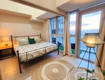 a bedroom with a bed and a large window at BGC Uptown Parksuites King Bed with Balcony Sunset and City View in Manila