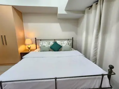 a bedroom with a bed with white sheets and blue pillows at BGC Uptown Parksuites King Bed with Balcony Sunset and City View in Manila