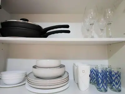 a shelf with plates and bowls and wine glasses at BGC Uptown Parksuites King Bed with Balcony Sunset and City View in Manila