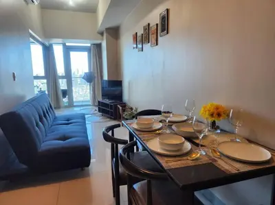 a dining room with a table and a blue couch at BGC Uptown Parksuites King Bed with Balcony Sunset and City View in Manila