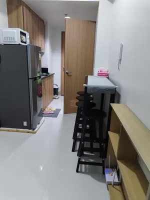 a kitchen with a refrigerator and a counter with stools at Cozy 642 shore3 residence tower2 near MOA in Manila