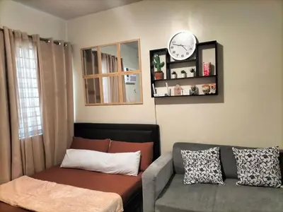 a living room with a couch and a clock on the wall at STANFORD SUITES 3 in Silang