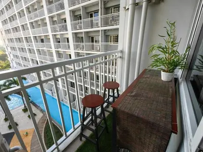 a balcony with two stools and a view of a building at Comfy unit at SMDC Breeze Residences near PICC, MOA, NAIA Airport, CCP with a view! in Manila