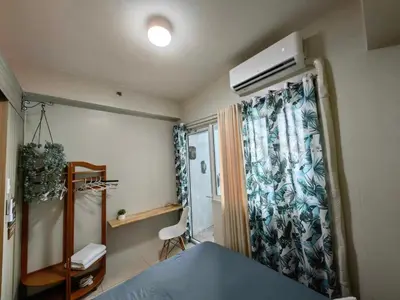 a bedroom with a bed and a window with a curtain at Comfy unit at SMDC Breeze Residences near PICC, MOA, NAIA Airport, CCP with a view! in Manila