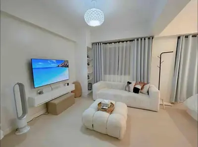 a living room with two white couches and a flat screen tv at Relax in style: Modern Airbnb and Netflix in Manila