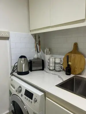 a kitchen counter with a washing machine and a sink at Relax in style: Modern Airbnb and Netflix in Manila