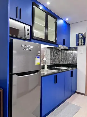a kitchen with blue cabinets and a stainless steel refrigerator at Deluxe Executive Corner Unit in Makati in Manila