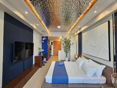 a bedroom with a large white bed and a tv at Deluxe Executive Corner Unit in Makati in Manila