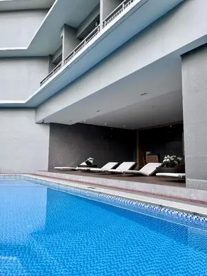 a swimming pool with a row of chairs next to a building at Deluxe Executive Corner Unit in Makati in Manila