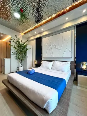 a bedroom with a large bed with a blue blanket at Deluxe Executive Corner Unit in Makati in Manila