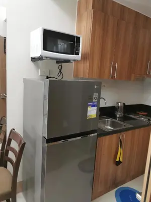 a small kitchen with a microwave and a refrigerator at Moa shore 3 staycation in Manila