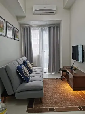 a living room with a couch and a television at Moa shore 3 staycation in Manila