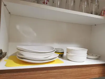 a pile of plates and bowls sitting on a shelf at Moa shore 3 staycation in Manila