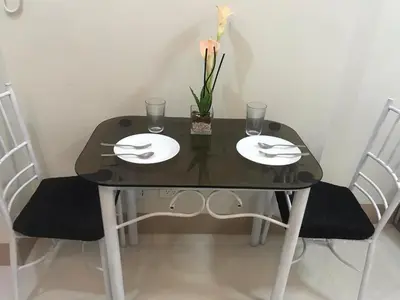 a black table with two plates and a flower on it at Cozy 1-bedroom unit in Shore 3 Residences in Manila