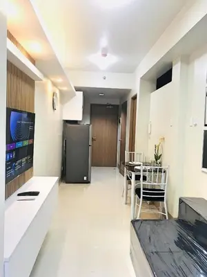 a kitchen and dining room with a table and a refrigerator at Cozy 1-bedroom unit in Shore 3 Residences in Manila