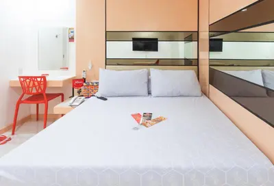 a bedroom with a large white bed with a red chair at Hotel Sogo Guadalupe in Manila