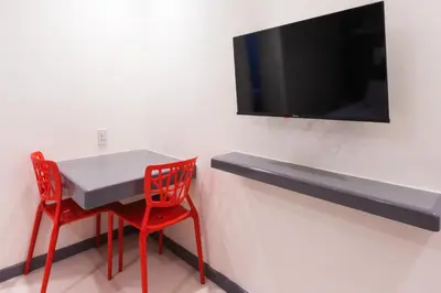 a table with two red chairs and a tv on a wall at Hotel Sogo Guadalupe in Manila